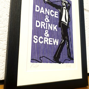 May include: Framed art print with a black and white illustration of a man in a suit, with the words "DANCE & DRINK & SCREW" in white on a blue striped background. The print is in a black frame.