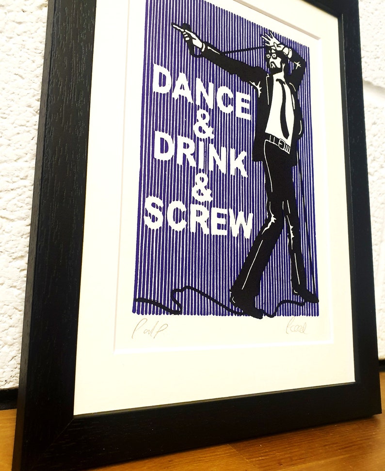May include: Framed art print with a black and white illustration of a man in a suit, with the words "DANCE & DRINK & SCREW" in white on a blue striped background. The print is in a black frame.