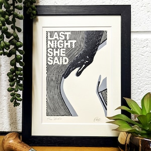 May include: Black and white print of a hand reaching towards a body with the text "Last Night She Said" in white. The print is signed "The Strokes" in the bottom left corner and "Leo" in the bottom right corner.