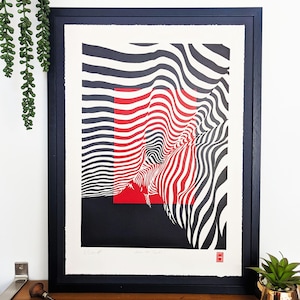 Könnte beinhalten: Gerahmter abstrakter Kunstdruck mit schwarzem Rahmen. Das Kunstwerk zeigt ein rotes Quadrat und schwarz-weiße Wellenlinien. Der Druck befindet sich auf weißem Papier und hat Text und einen roten Stempel in der unteren rechten Ecke.