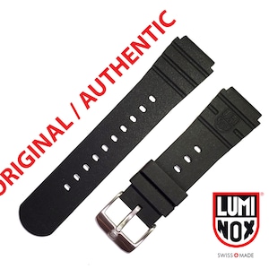 May include: Black rubber watch strap with a silver buckle. The strap has a textured surface and is labeled "LUMI NOX" with "SWISS MADE" below the logo.