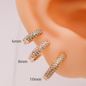 May include: Three gold hoop earrings with a pave setting of clear cubic zirconia stones. The hoops are 6mm, 8mm, and 10mm in diameter.