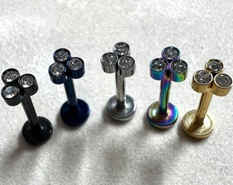 Puede incluir: Cinco piezas de joyería corporal de diferentes colores con tres piedras transparentes en cada una. La joyería está hecha de metal y tiene un estilo de barra.
