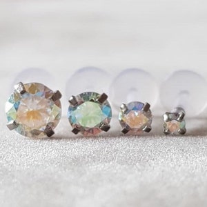 Op de afbeelding: Drie oorbel studs met iriserende edelstenen in verschillende maten. De oorbel studs zijn gezet in zilver en hebben een helder, facetgeslepen ontwerp.