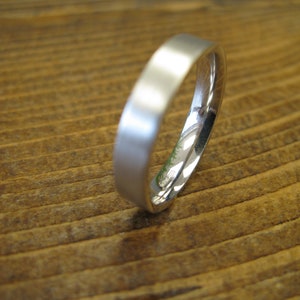 May include: A simple silver wedding band with a smooth, polished finish.
