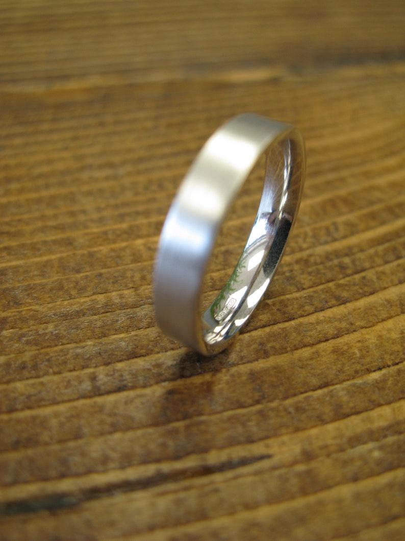 May include: A simple silver wedding band with a smooth, polished finish.