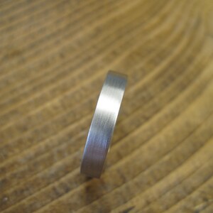 May include: A silver band ring with a brushed finish.