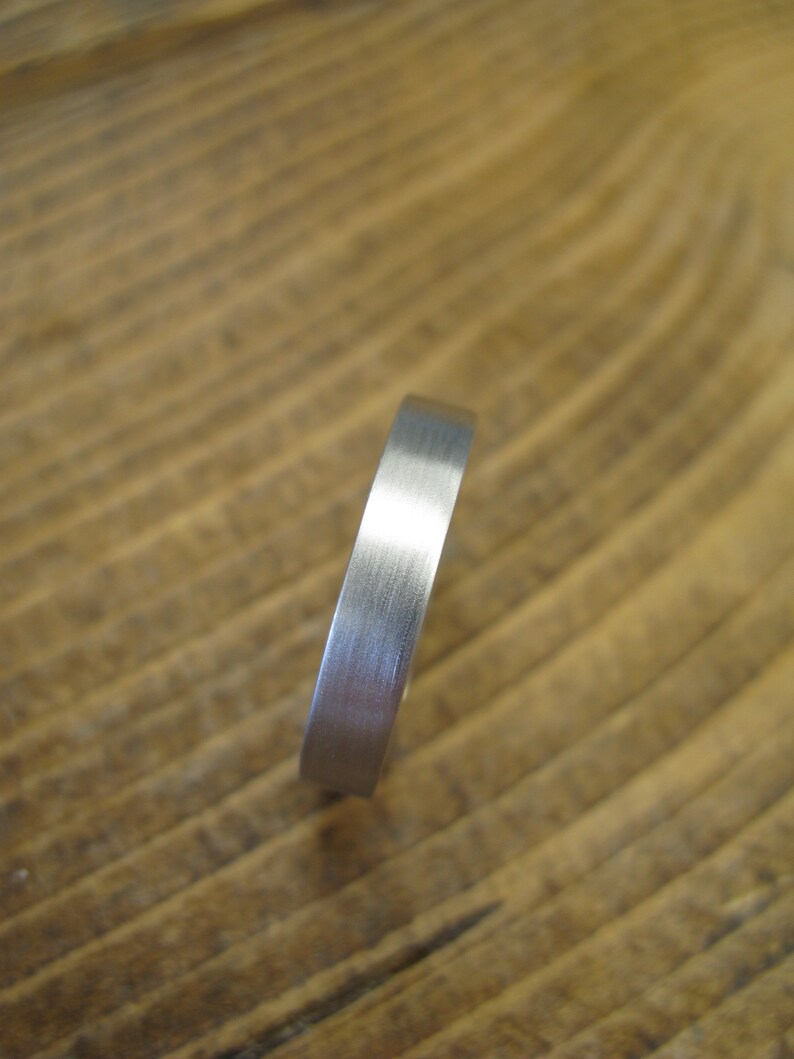 May include: A silver band ring with a brushed finish.