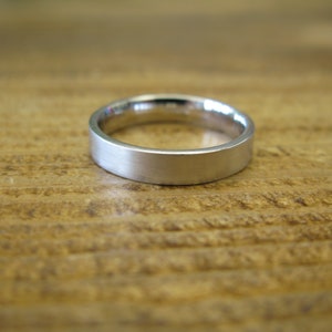 May include: A simple silver wedding band with a brushed finish.