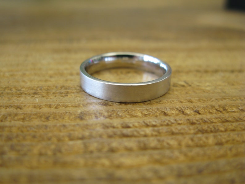 May include: A simple silver wedding band with a brushed finish.