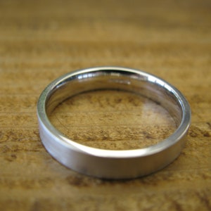 May include: A simple silver wedding band with a brushed finish.