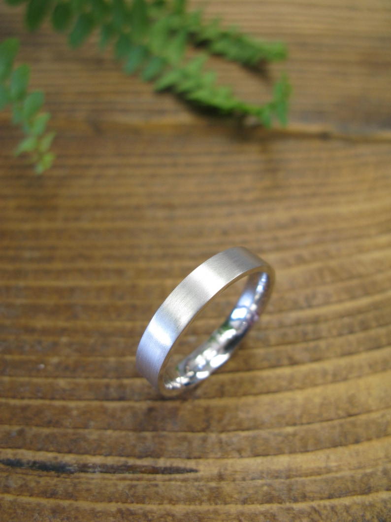 May include: A simple silver wedding band with a brushed finish.