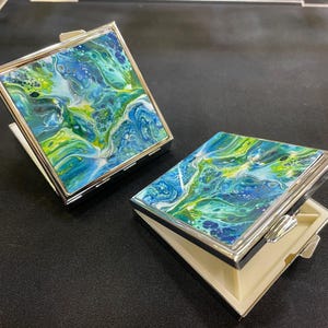 Boîte à pilules carrée en miroir avec compartiments. Mettant en vedette un magnifique art abstrait unique de Felicity Osborne de Flowbyflo. Édition limitée