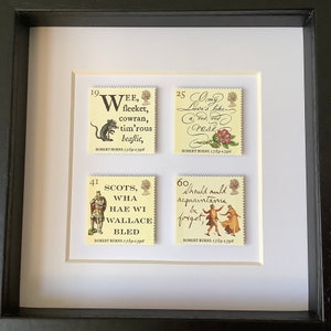 May include: Four vintage postage stamps featuring quotes from Robert Burns, the Scottish poet. The stamps are framed in a black frame with a white mat. The stamps are yellow with black text and illustrations.