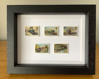 May include: A framed collection of five vintage British postage stamps featuring steam locomotives. The stamps are in mint condition and feature the names of the locomotives, including "Flying Scotsman", "Golden Arrow", and "Royal Scot".