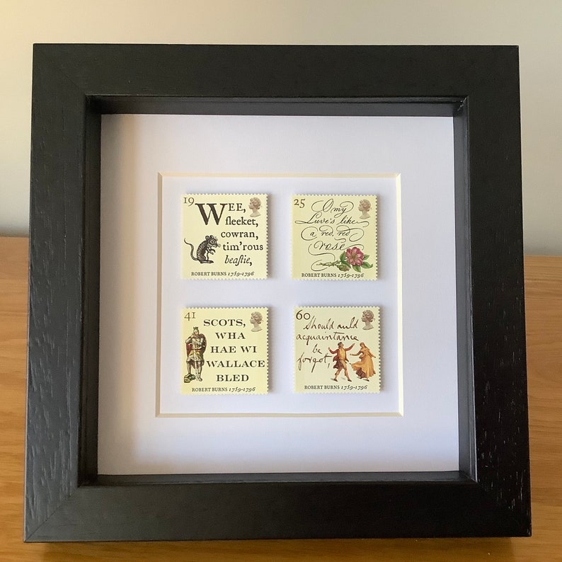 May include: Four vintage postage stamps featuring quotes from Robert Burns, the Scottish poet. The stamps are framed in a black frame with a white mat. The stamps feature illustrations of a mouse, a rose, a knight, and a couple dancing.