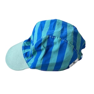 Op de afbeelding: Een blauw en turquoise gestreepte pet met een lichtgroenkleurig vizier. De pet heeft verticale strepen en een gebogen vizier. De stof lijkt licht van gewicht. De pet is ontworpen voor bescherming tegen de zon en vrijetijdskleding.