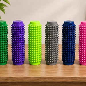 May include: Six cylindrical massage rollers arranged in a row, each featuring a textured surface with numerous small, pointed spikes. The rollers are colored in green, purple, lime green, gray, dark blue, and bright pink, all standing upright.