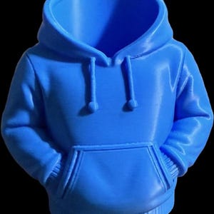 May include: A vibrant blue miniature hoodie with a front pocket and drawstring hood. The small garment is a solid color and appears to be made of a soft material. The hoodie is a novelty item.