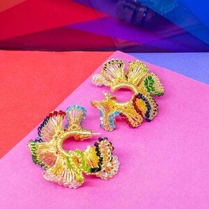 May include: A pair of gold hoop earrings with colorful beads. The earrings are made of wire and have a delicate, intricate design.