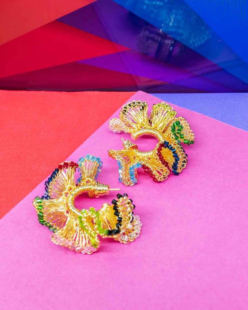 May include: A pair of gold hoop earrings with colorful beads. The earrings are made of wire and have a delicate, intricate design.