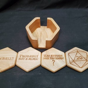 May include: Wooden box with a hinged lid and four hexagonal coasters. The coasters have engraved text: "Fireball!", "Probably not a mimic", "Has anyone seen the rogue?", and a 20-sided die with the number 20.