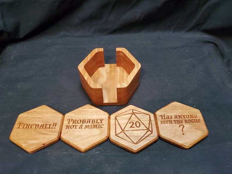 May include: Wooden hexagonal coasters with engraved text and a 20-sided die. The coasters feature phrases like "Fireball!" and "Probably not a mimic". The die is in the center of the coasters. The coasters are in a wooden holder.