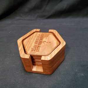 May include: A set of six wooden coasters in a hexagonal holder. The coasters are engraved with the text "Has anyone seen the booze?" and a question mark.