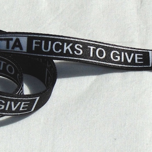 May include: Black and white lanyard with the text "OUTTA F*CKS TO GIVE" printed on it. The lanyard has a silver metal clip.