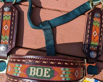 May include: A brown leather horse halter with a green nylon rope and a beaded design. The halter has the name "ROE" beaded into the leather. The halter is on a wooden surface. The halter is made by Weaver Leather and is a basic adjustable halter.