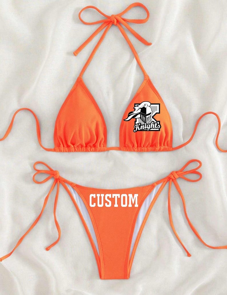 May include: Orange bikini top and bottom with a white graphic of a knight's helmet and the word "Knights". The bottom has the word "CUSTOM" printed on it.