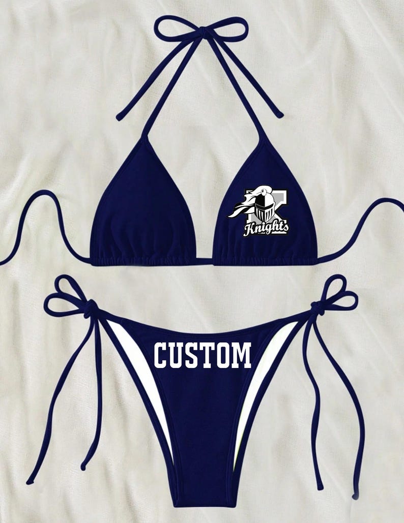 May include: Navy blue bikini with a white graphic of a knight's helmet and the word "Knights". The bottom of the bikini has the word "CUSTOM" printed in white.