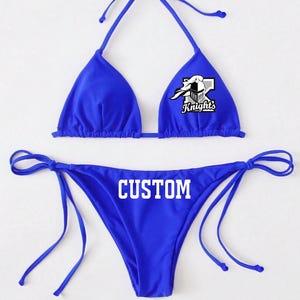 May include: A royal blue bikini with a white graphic of a knight's helmet and the word "Knights" on the top and the word "CUSTOM" on the bottom.