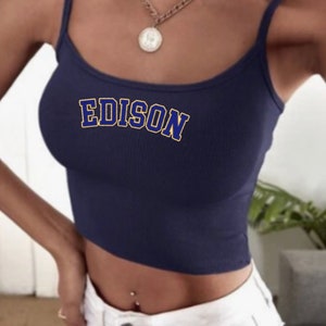May include: A navy blue crop top with thin straps and the word "EDISON" printed in yellow outlined in blue.
