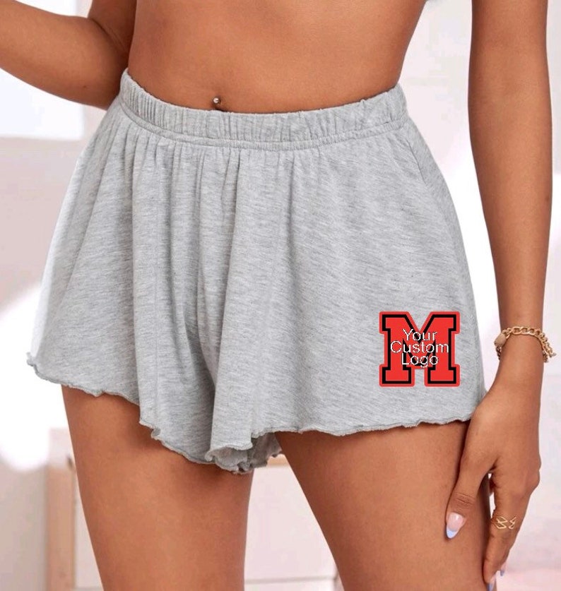 May include: Gray shorts with a ruffled hem and a red "Your Custom Logo" patch on the right leg.