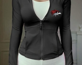 May include: Black zip-up athletic jacket with a white tank top underneath. The jacket features a red and gray hawk logo on the chest. The jacket has a high collar and long sleeves. The model is wearing white athletic pants.