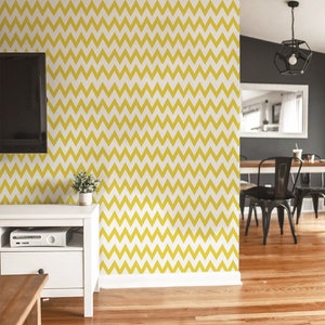 Puede incluir: Un papel tapiz con patrón de chevron amarillo y blanco con un zócalo blanco. El papel tapiz está en una sala de estar con un centro de entretenimiento blanco y una mesa de café de madera.