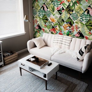 May include: A white sofa with a white throw blanket and a black and white patterned pillow sits in front of a wall with a tropical wallpaper featuring a repeating pattern of green leaves, pink flamingos, and colorful flowers.