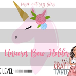 Puede incluir: Cabeza de unicornio rosa con un cuerno dorado y una rosa rosa con hojas verdes. El unicornio lleva un lazo azul. El texto "Unicorn Bow Holder" está debajo del unicornio. El texto "on the CRAFT TABLE" está debajo del texto "Unicorn Bow Holder".