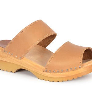 May include: Tan leather peep-toe clog sandals with two straps and a wooden platform sole.