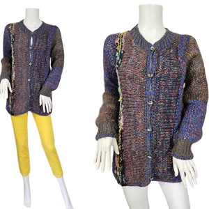May include: A long-sleeved cardigan with a button-up front. The cardigan is made of a chunky knit yarn in a mix of brown, blue, and multi-colored flecks.