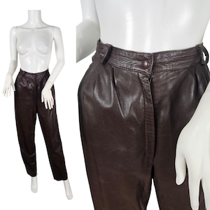 Könnte beinhalten: Dunkelbraune Lederhose mit hohem Bund und Knopfverschluss. Die Hose hat eine Faltenfront und ein gerades Bein. Das Leder scheint weich zu sein. Auf einer Schaufensterpuppe präsentiert.