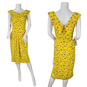 May include: A vintage yellow dress with a floral pattern. The dress features a ruffled neckline and a knee-length skirt. The floral pattern includes blue, red, and green accents. The dress is displayed on a mannequin.