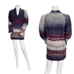 May include: A long-sleeved, V-neck sweater in shades of navy, burgundy, and cream. The sweater features a geometric pattern around the waist and cuffs. The front and back views are displayed on a mannequin.