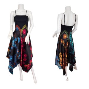 May include: A black midi dress with a square neckline and spaghetti straps. The skirt features a vibrant floral print in shades of red, blue, and orange. The dress is displayed on a mannequin.
