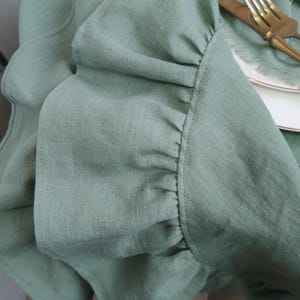 A close-up view of a green ruffled fabric, with a gold fork and knife placed on a white plate.