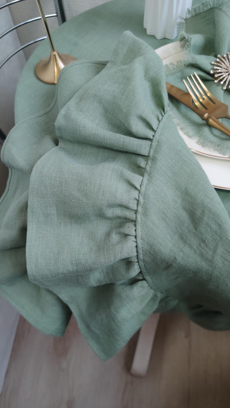 A close-up view of a green ruffled fabric, with a gold fork and knife placed on a white plate.