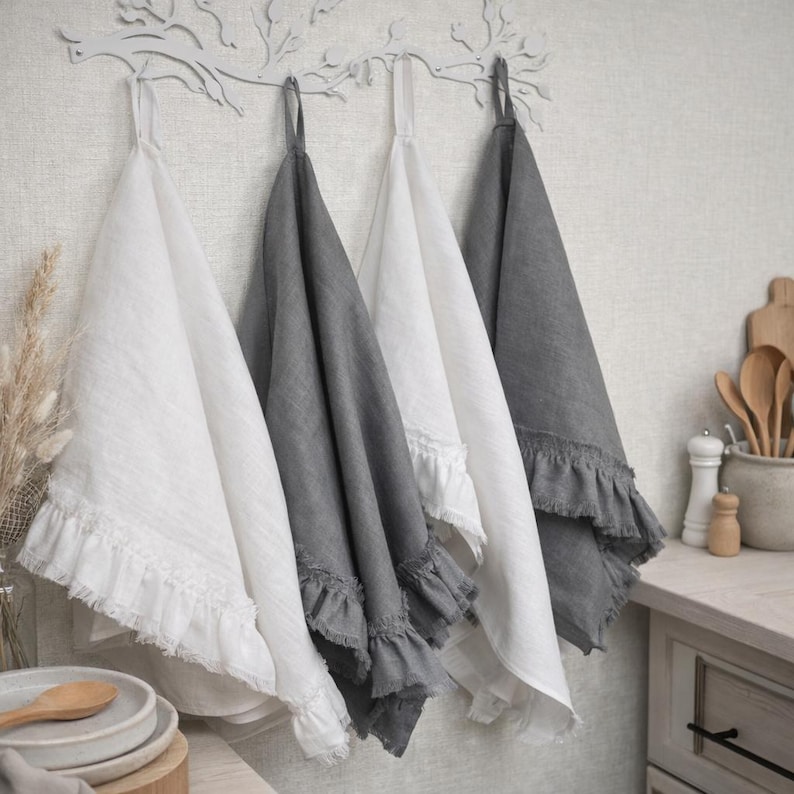 a set of three hanging kitchen towels, each with a different color and texture, arranged on a wall-mounted rack.