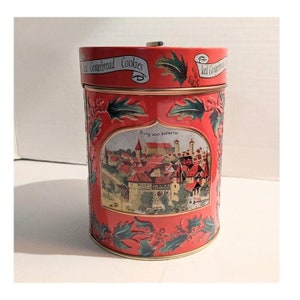 Puede incluir: Lata de galletas de Navidad de metal rojo con una imagen de una ciudad medieval y el texto "Burg vom Hallertor" en la parte delantera. La tapa tiene un diseño de acebo y el texto "Old Gingerbread Cookies".