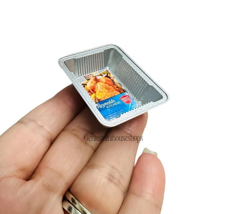 May include: Miniature Reynolds Kitchens heavy duty foil baking tray with a label showing a roasted chicken. The tray is rectangular with a corrugated design. The label is blue and white.